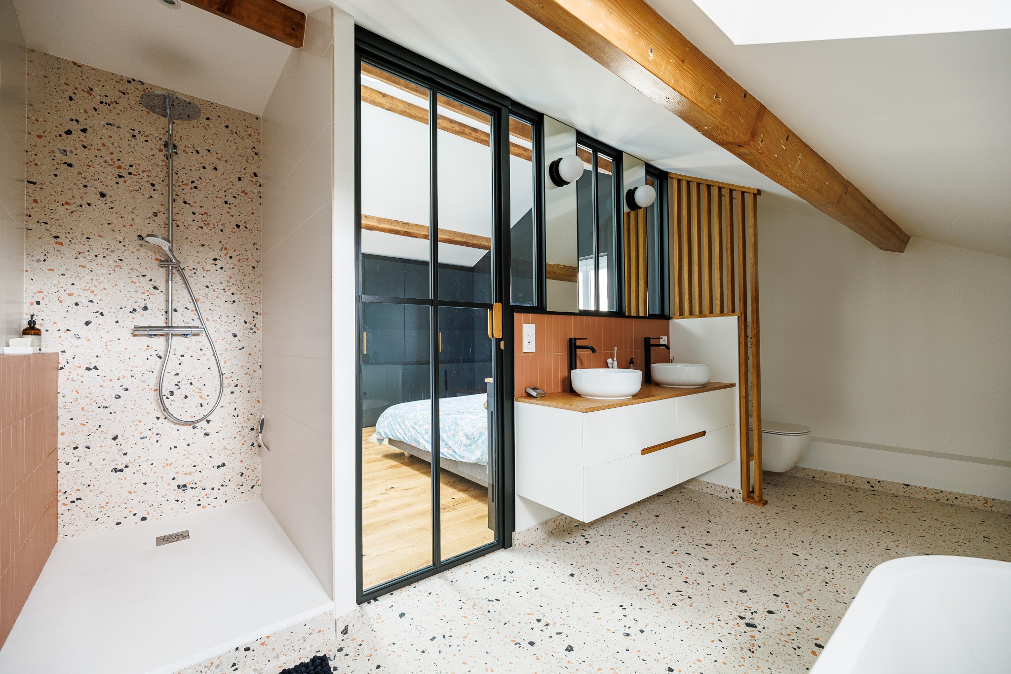 Salle de bains avec douche en terrazzo, double vasque et poutres apparentes